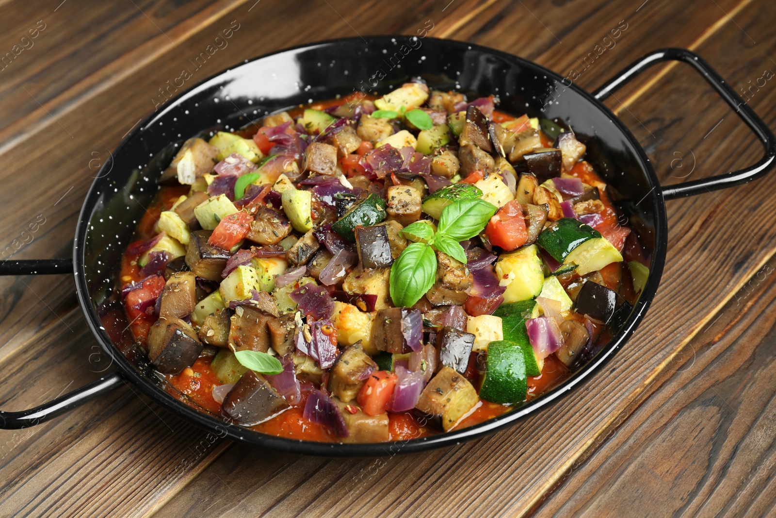 Photo of Delicious ratatouille in baking dish on wooden table, closeup