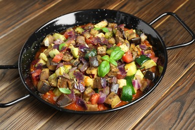 Photo of Delicious ratatouille in baking dish on wooden table, closeup