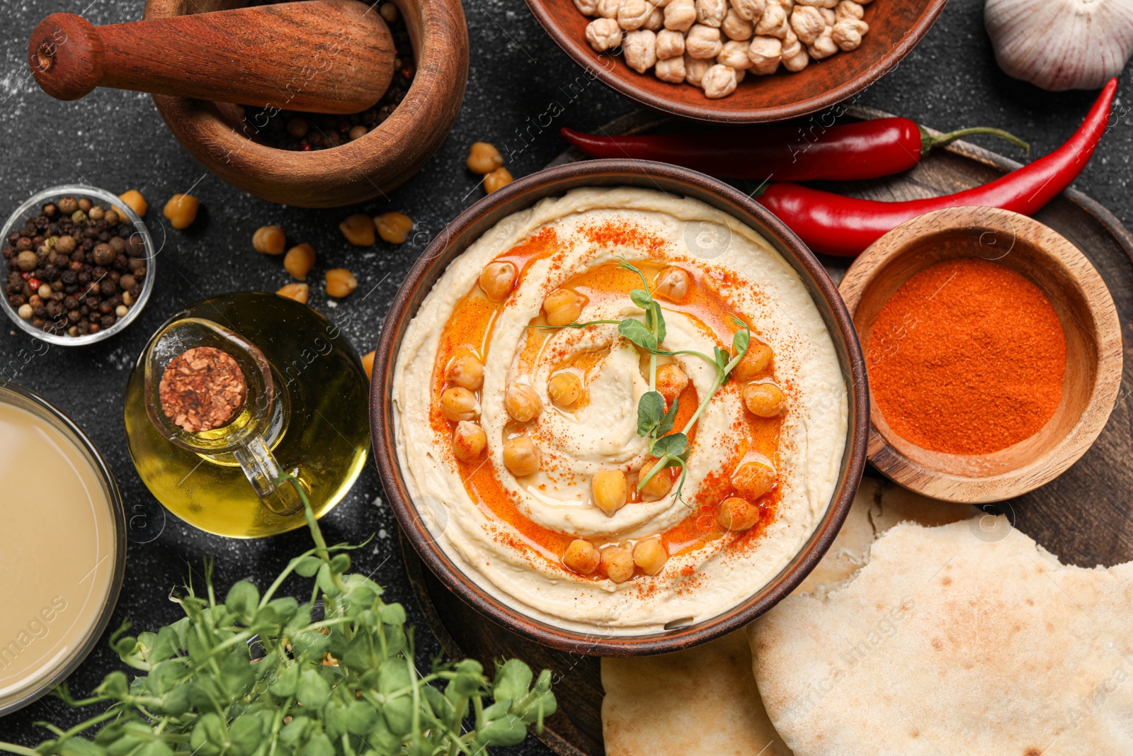 Photo of Delicious hummus with chickpeas and different ingredients on grey table, flat lay