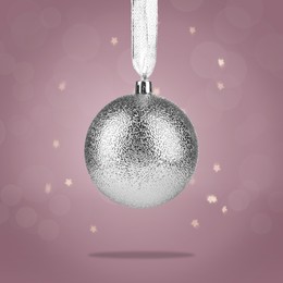 Image of Beautiful silver Christmas ball hanging on color background