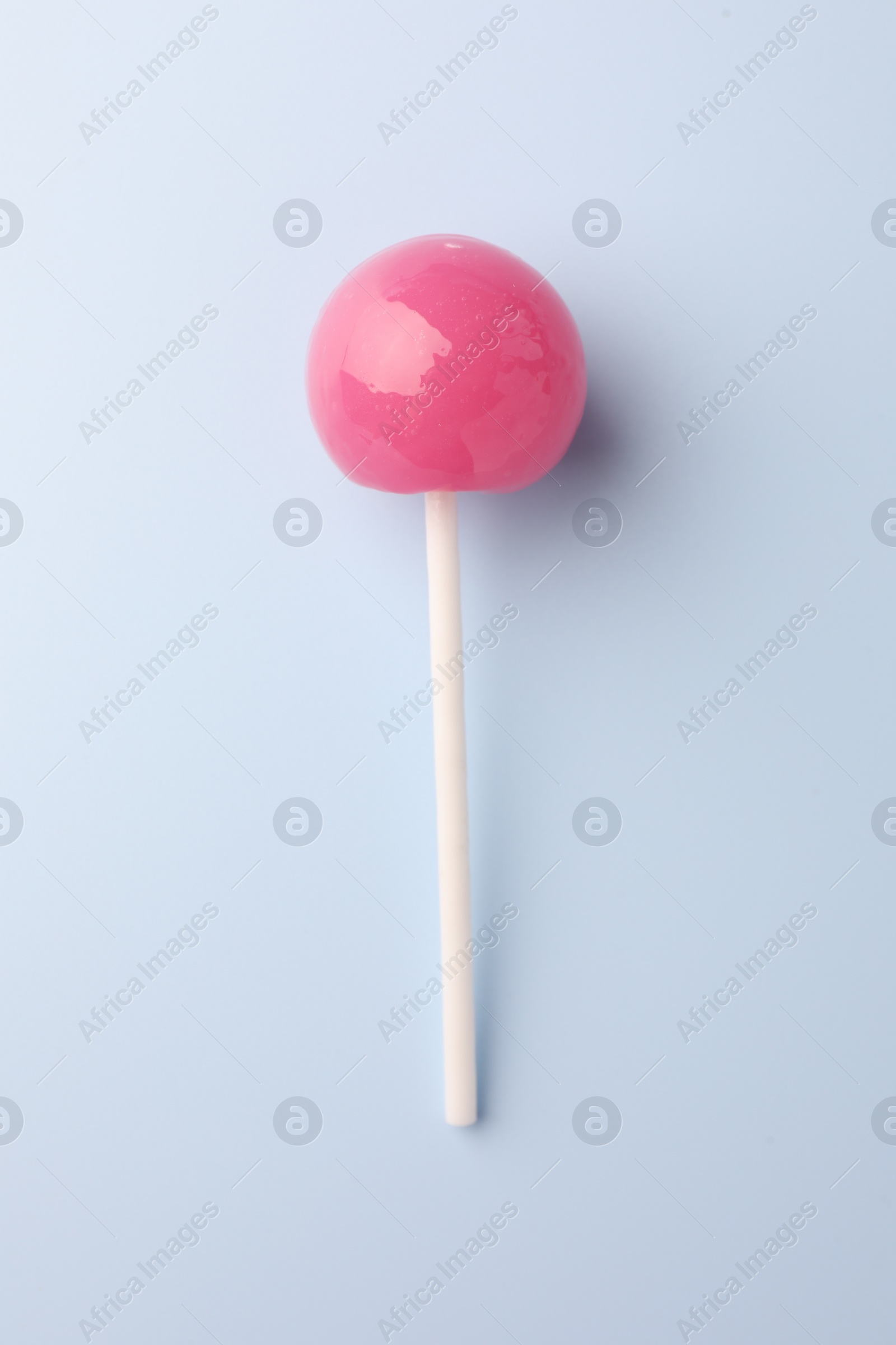 Photo of One tasty lollipop on light blue background, top view