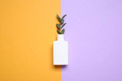 Photo of Bottle with twig on color background, top view