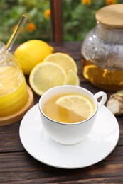 Cup of delicious tea with lemon and honey on wooden table