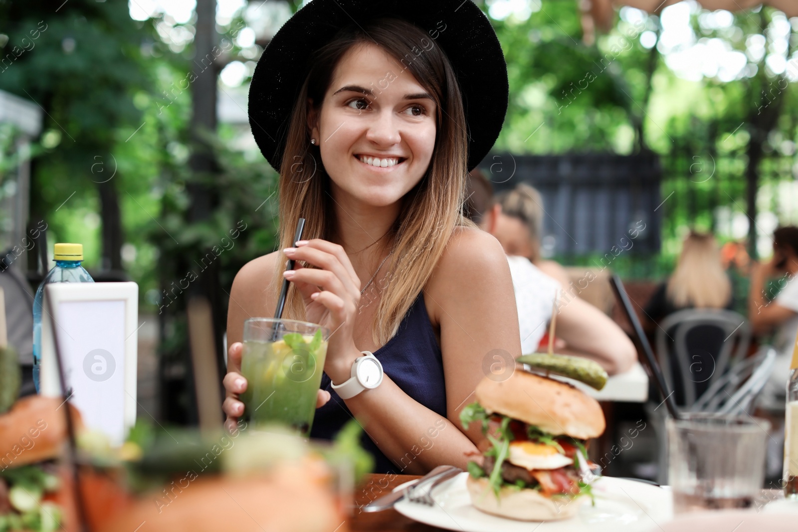 Photo of Woman with glass of tasty lemonade at table in cafe