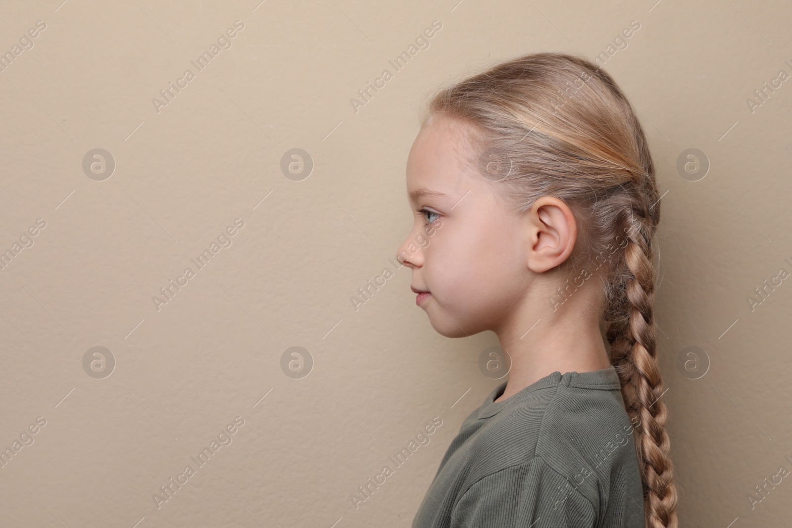 Photo of Profile portrait of cute little girl on beige background. Space for text