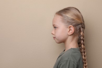 Photo of Profile portrait of cute little girl on beige background. Space for text