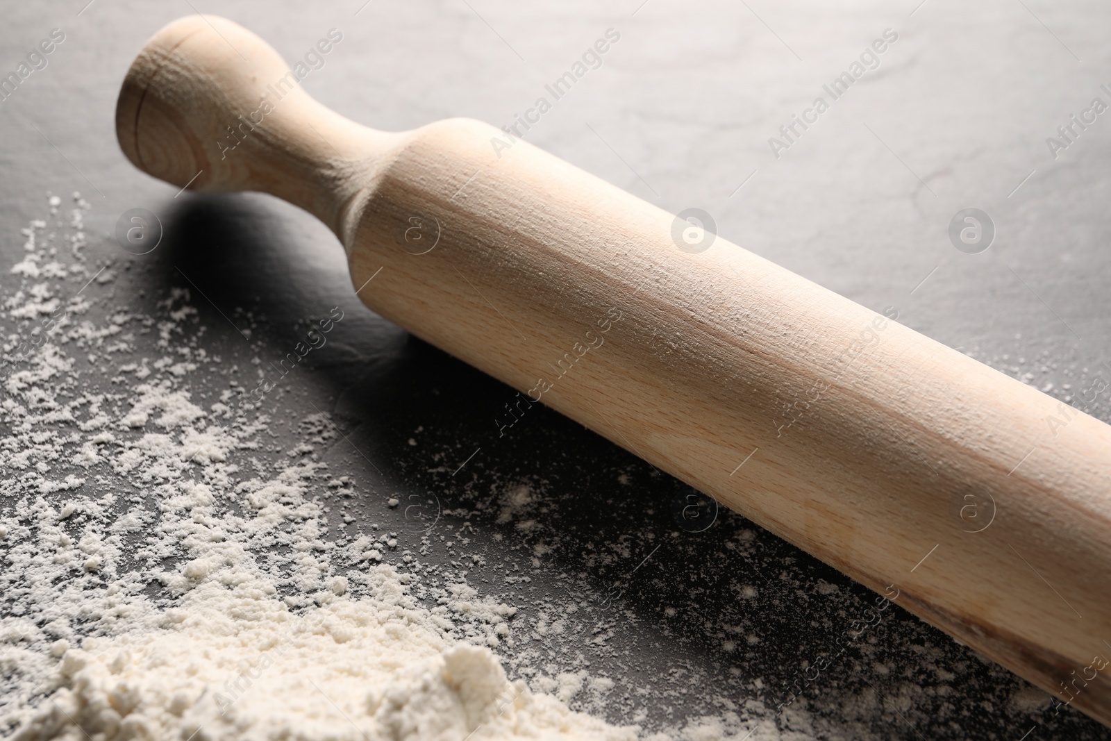 Photo of Pile of flour and rolling pin on grey textured table, closeup