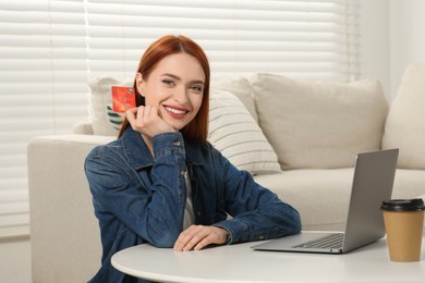 Photo of Happy woman with credit card near laptop at home. Online shopping