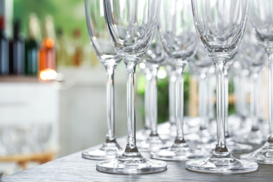 Photo of Empty glasses on wooden table against blurred background, closeup view