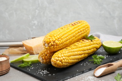 Photo of Delicious grilled corn cobs on grey table