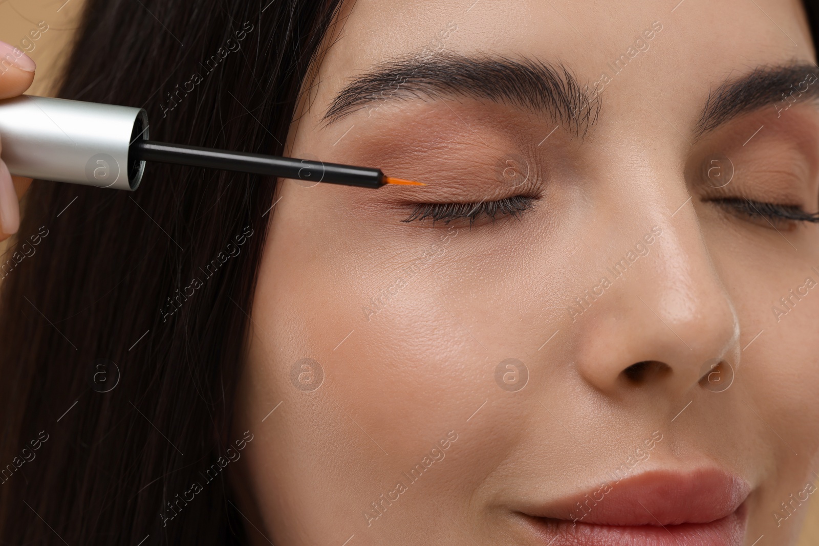 Photo of Beautiful woman applying serum onto her eyelashes, closeup. Cosmetic product