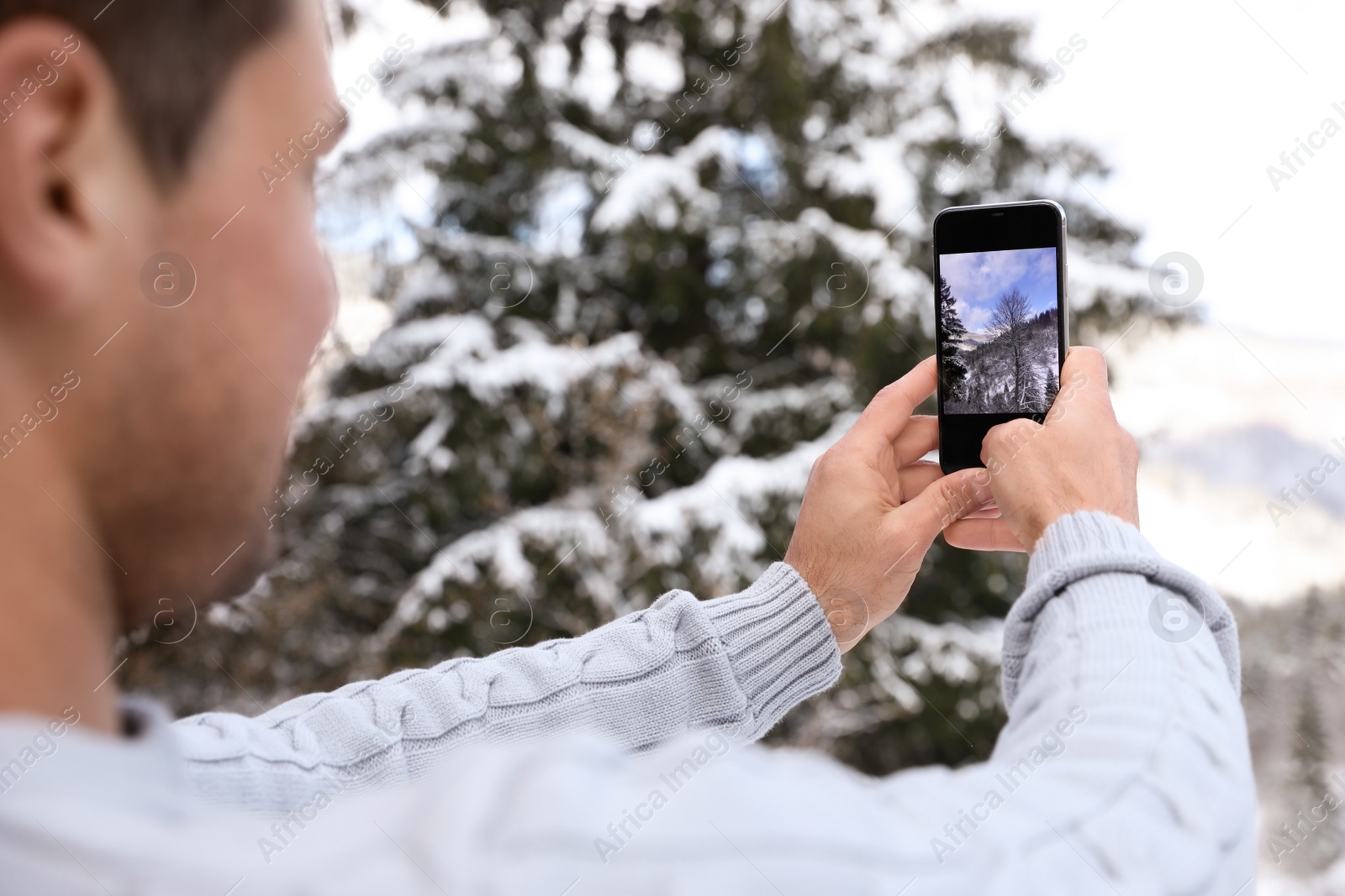 Photo of Man taking picture of snowy tree outdoors, closeup