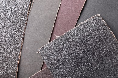 Photo of Many sheets of sandpaper as background, top view