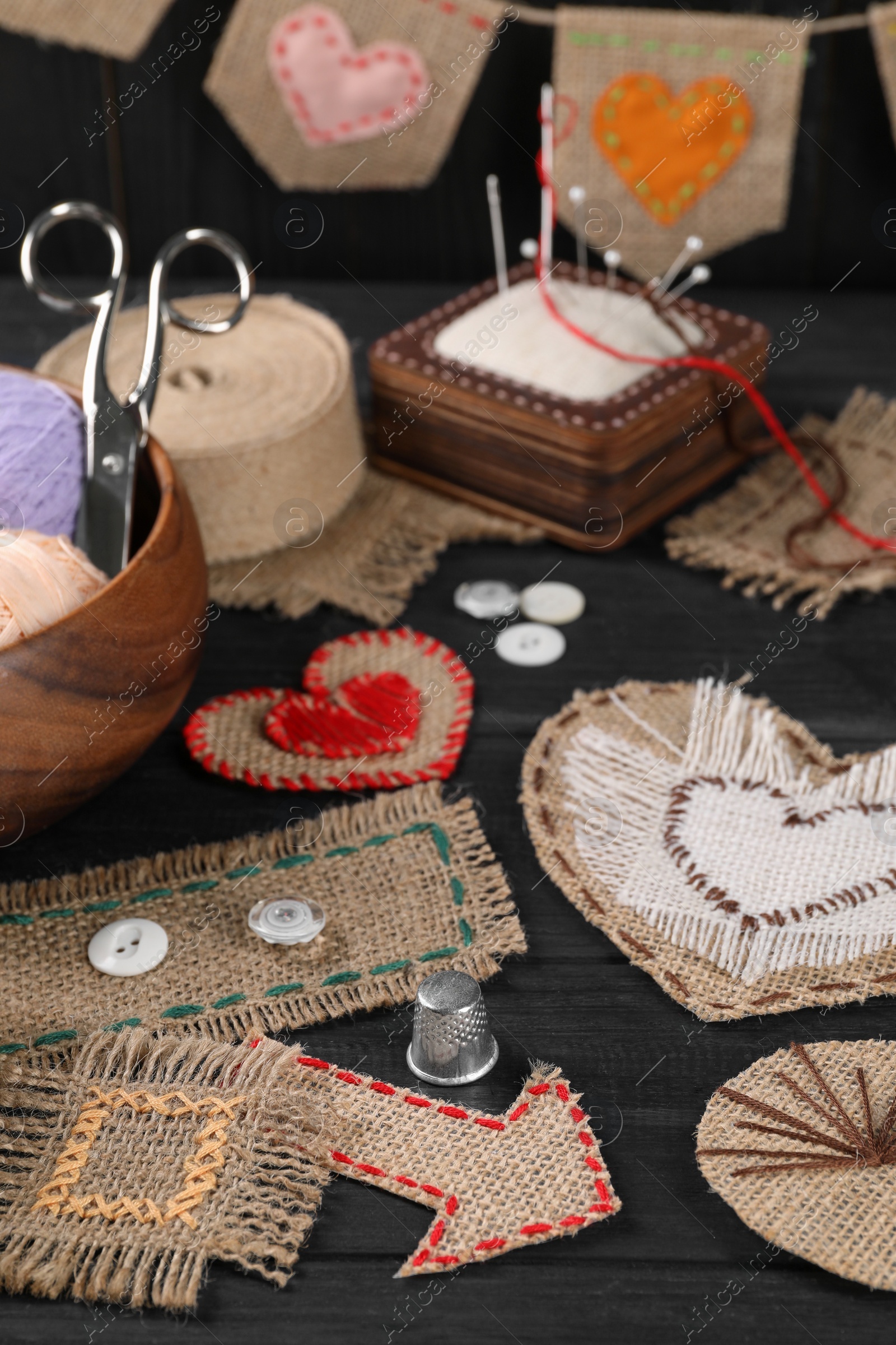 Photo of Pieces of burlap fabric with different stitches on black table, closeup