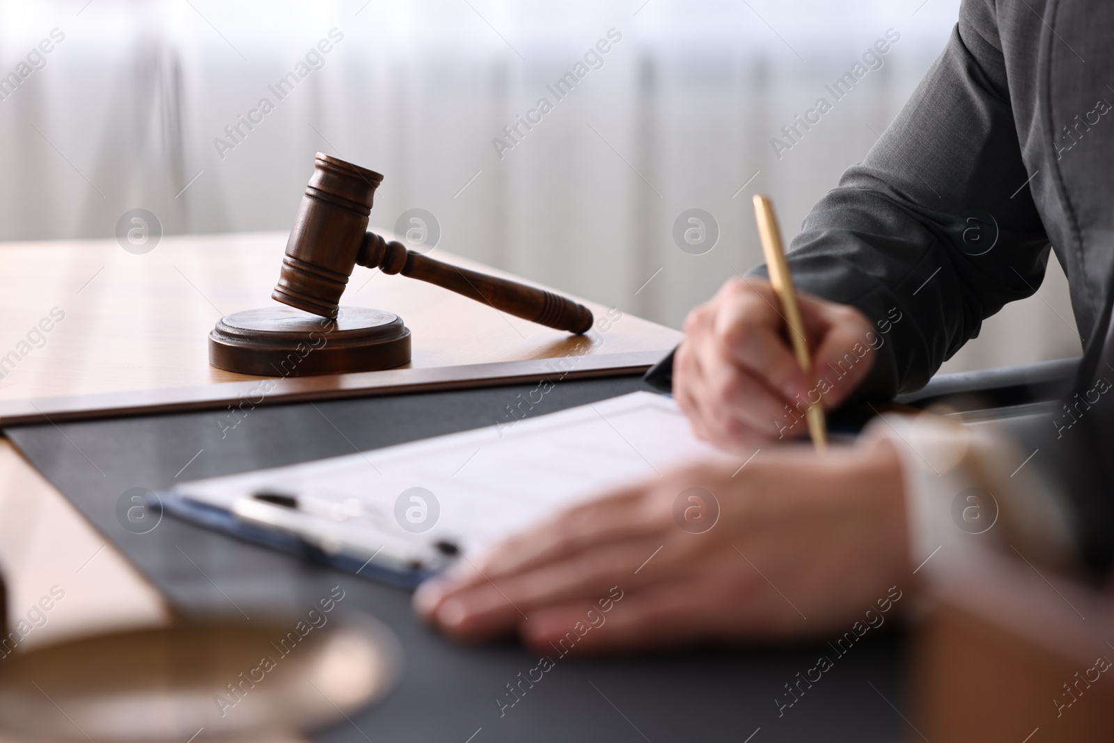 Photo of Notary writing notes at wooden table in office, closeup