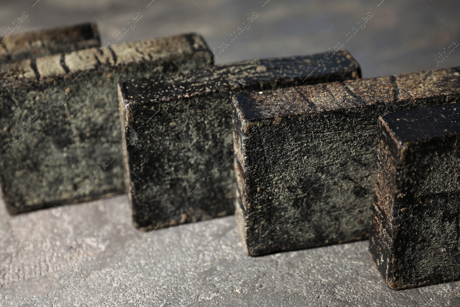 Photo of Natural tar soap on grey stone table, closeup