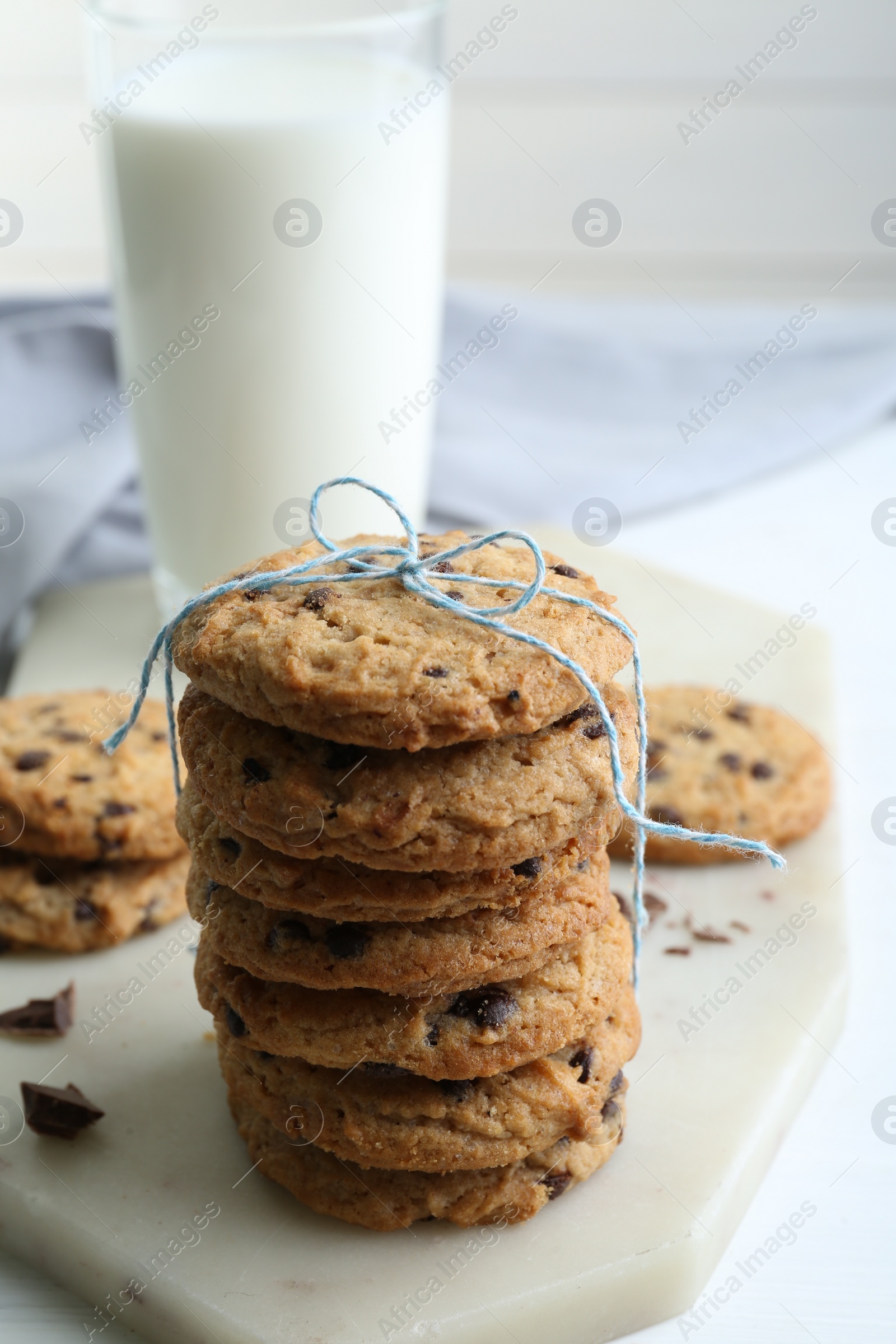 Photo of Tasty chocolate chip cookies and glass of milk on white wooden table, closeup