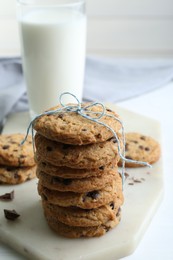 Photo of Tasty chocolate chip cookies and glass of milk on white wooden table, closeup