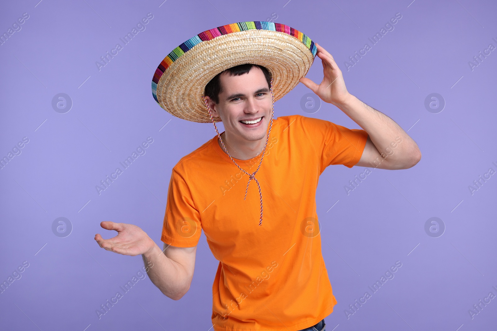 Photo of Young man in Mexican sombrero hat on violet background