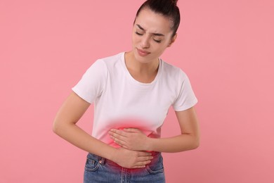 Woman suffering from stomach pain on pink background