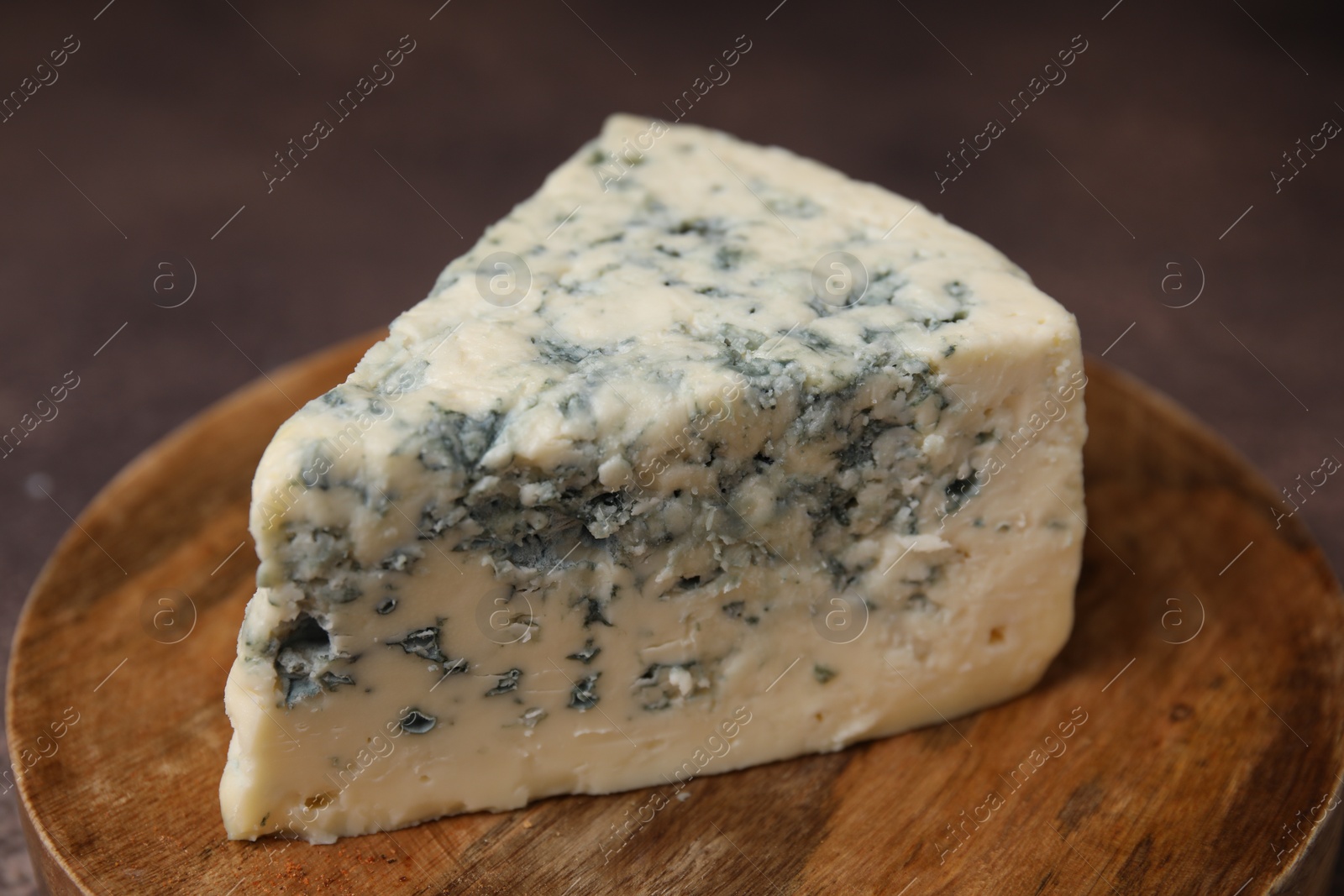Photo of Piece of tasty blue cheese on wooden board, closeup
