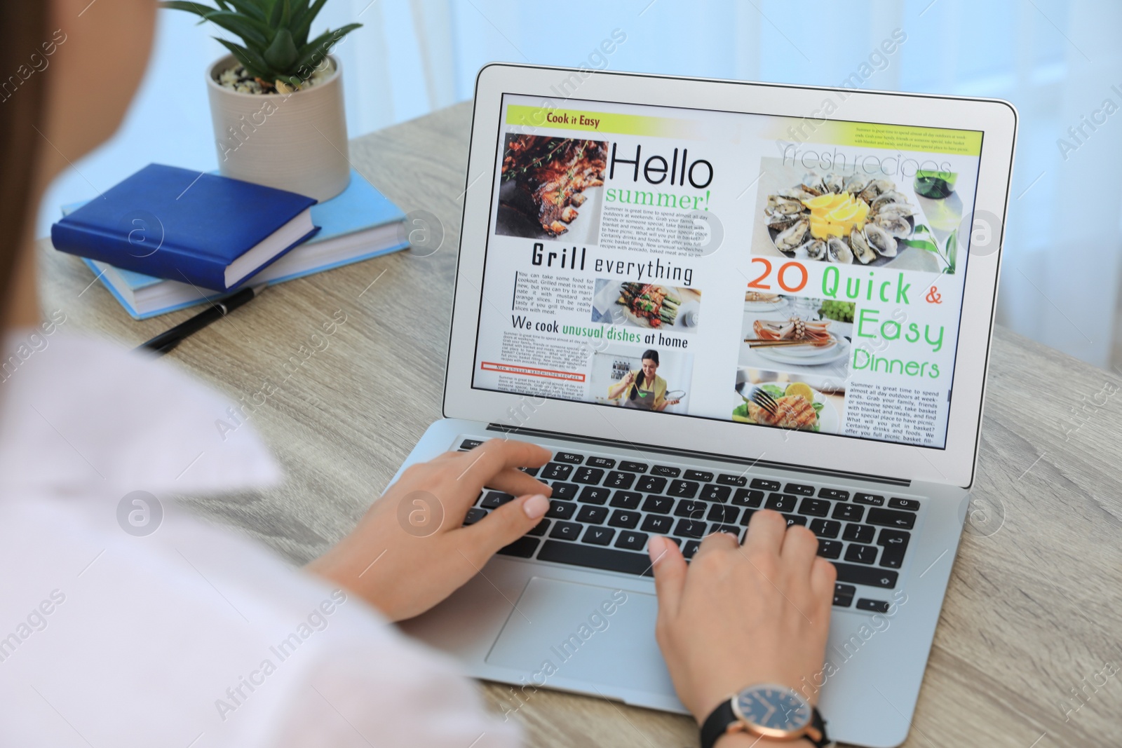 Photo of Woman reading online magazine on laptop at wooden table, closeup