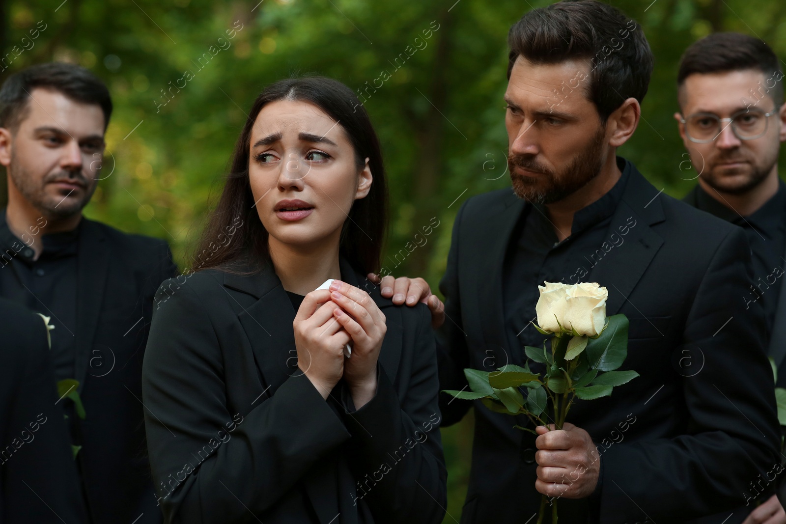 Photo of Funeral ceremony. Sad people in black clothes mourning outdoors