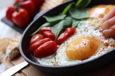 Photo of Delicious fried eggs with spinach, tomatoes and ham served on table, closeup