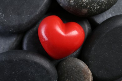 Photo of Red decorative heart on pebble stones, above view