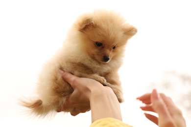 Woman holding small fluffy dog outdoors, closeup