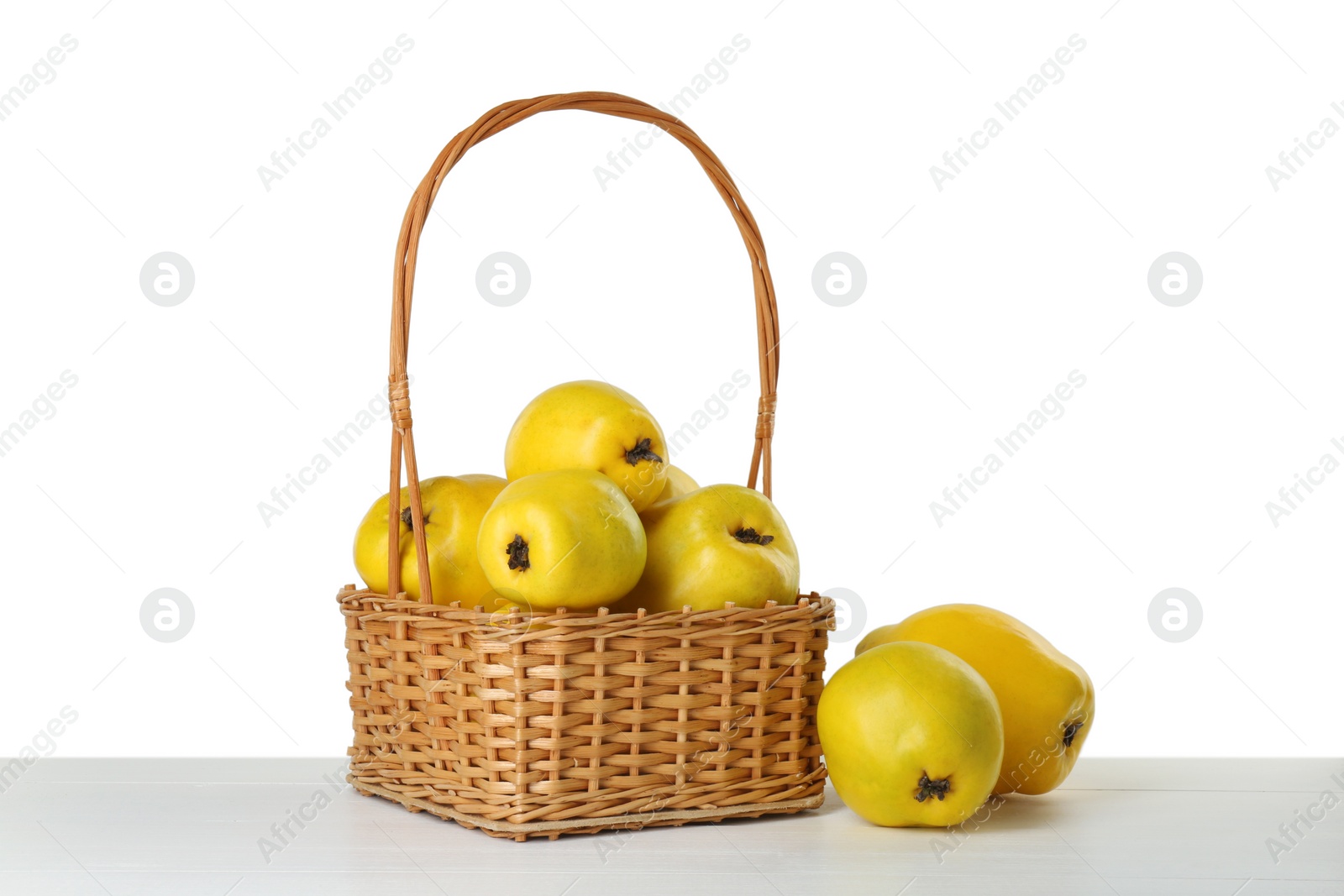 Photo of Basket with delicious fresh ripe quinces on light wooden table against white background
