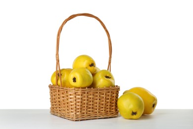 Photo of Basket with delicious fresh ripe quinces on light wooden table against white background