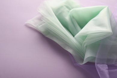 Photo of Beautiful tulle fabric on lilac background, space for text