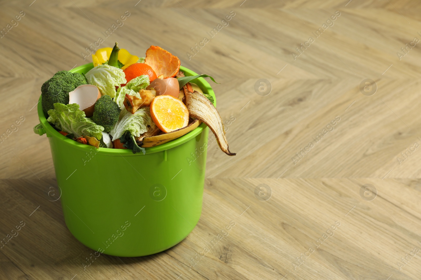 Photo of Trash bin with natural garbage on wooden background, space for text. Composting of organic waste