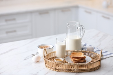 Photo of Tasty breakfast with toasted bread and milk on white marble table in kitchen