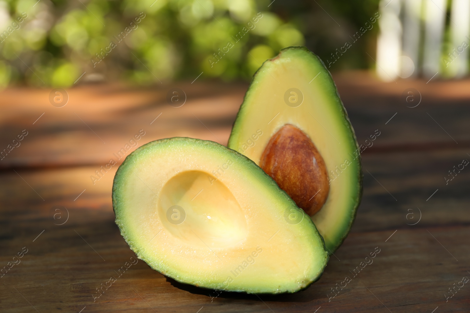 Photo of Halves of fresh avocado on wooden table outdoors, closeup