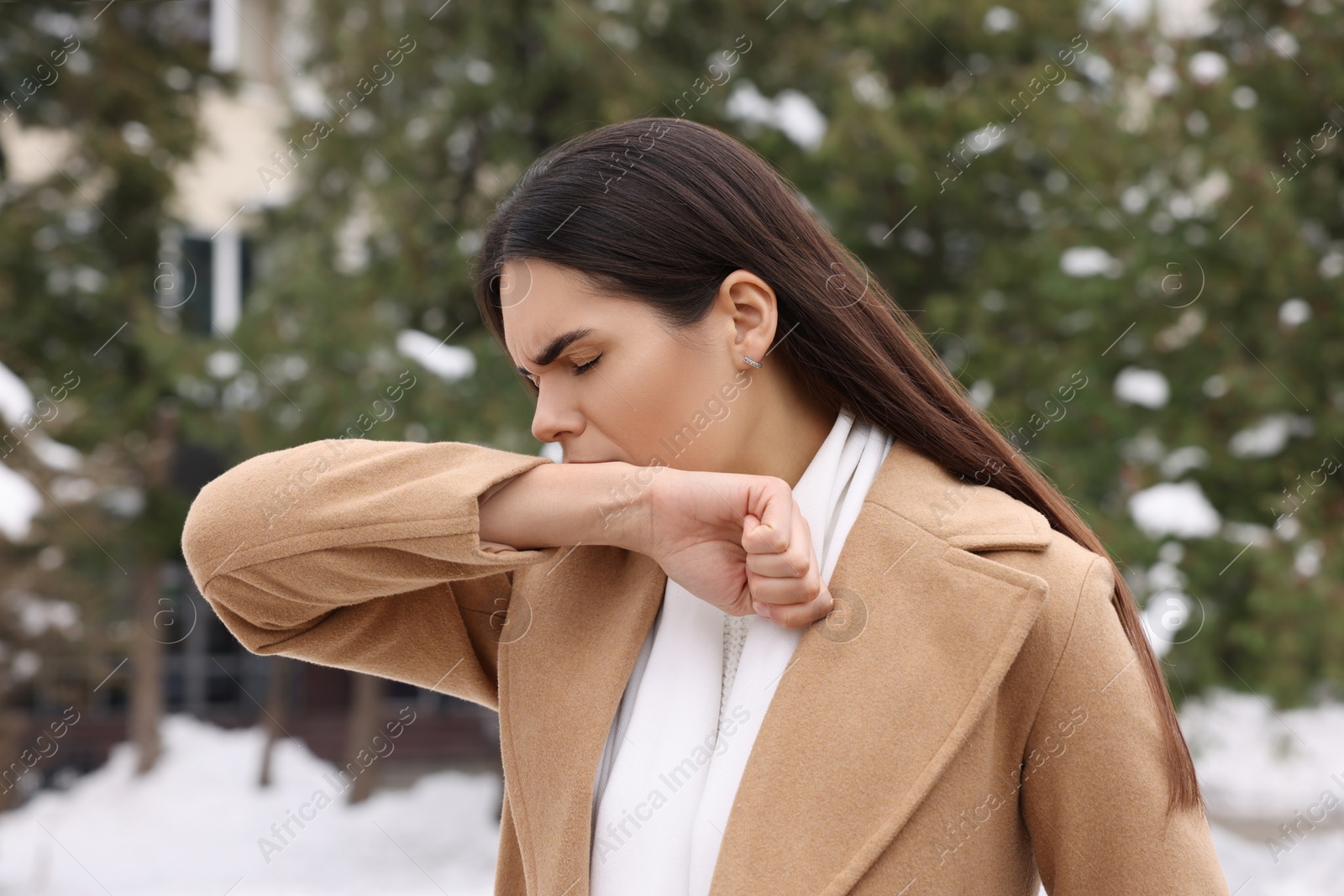 Photo of Woman in coat coughing outdoors. Cold symptoms