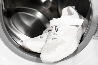 Stylish clean sneakers inside modern washing machine, closeup