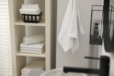 Photo of Shelving unit with stacked clean towels in bathroom