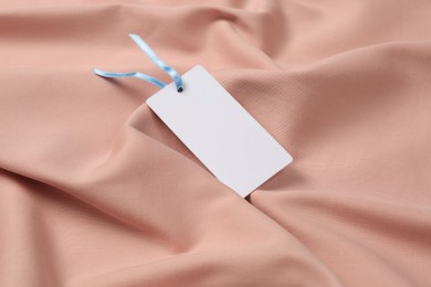 Photo of Blank white tag on pink fabric. Space or text