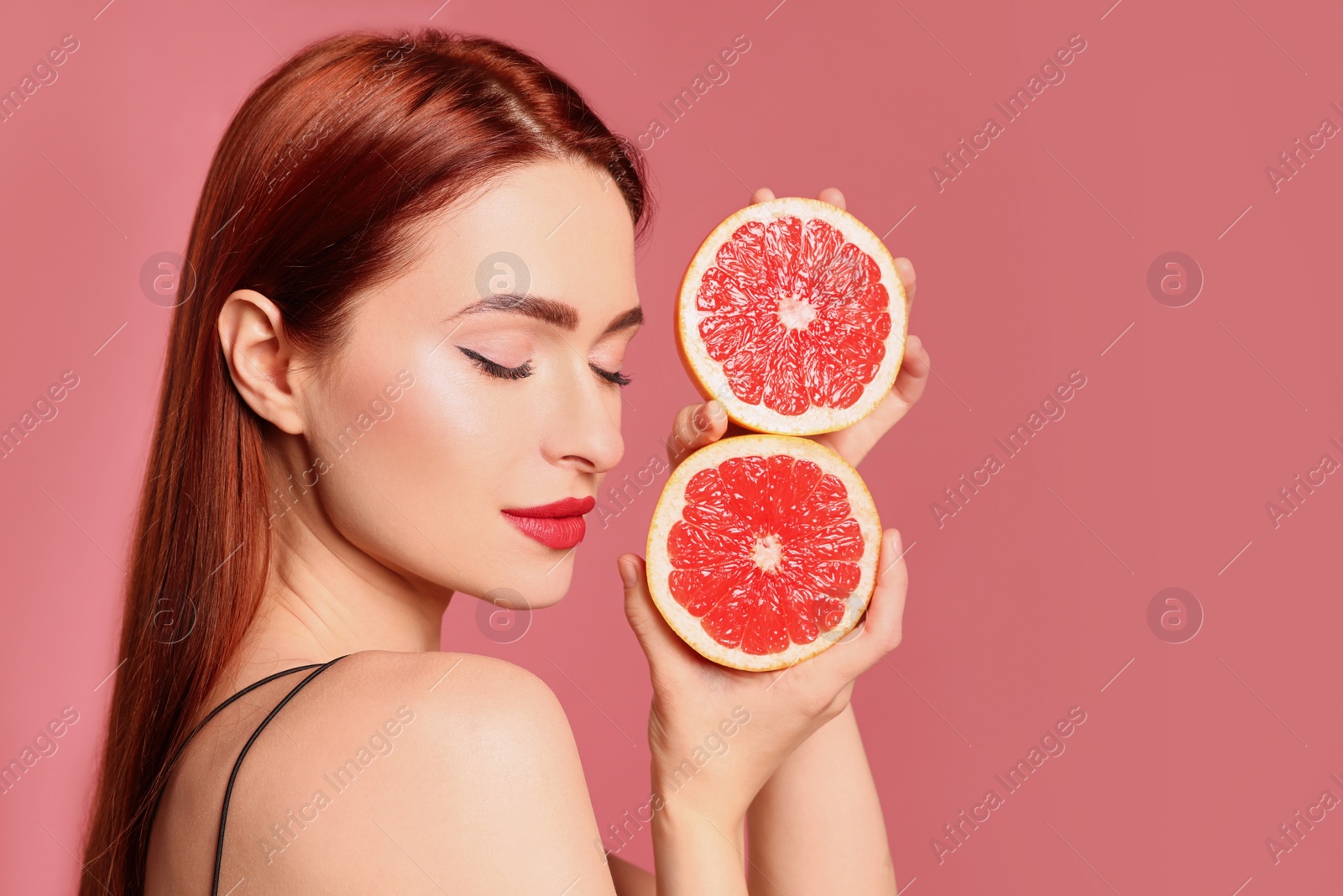 Photo of Beautiful woman with red dyed hair and grapefruits on pink background