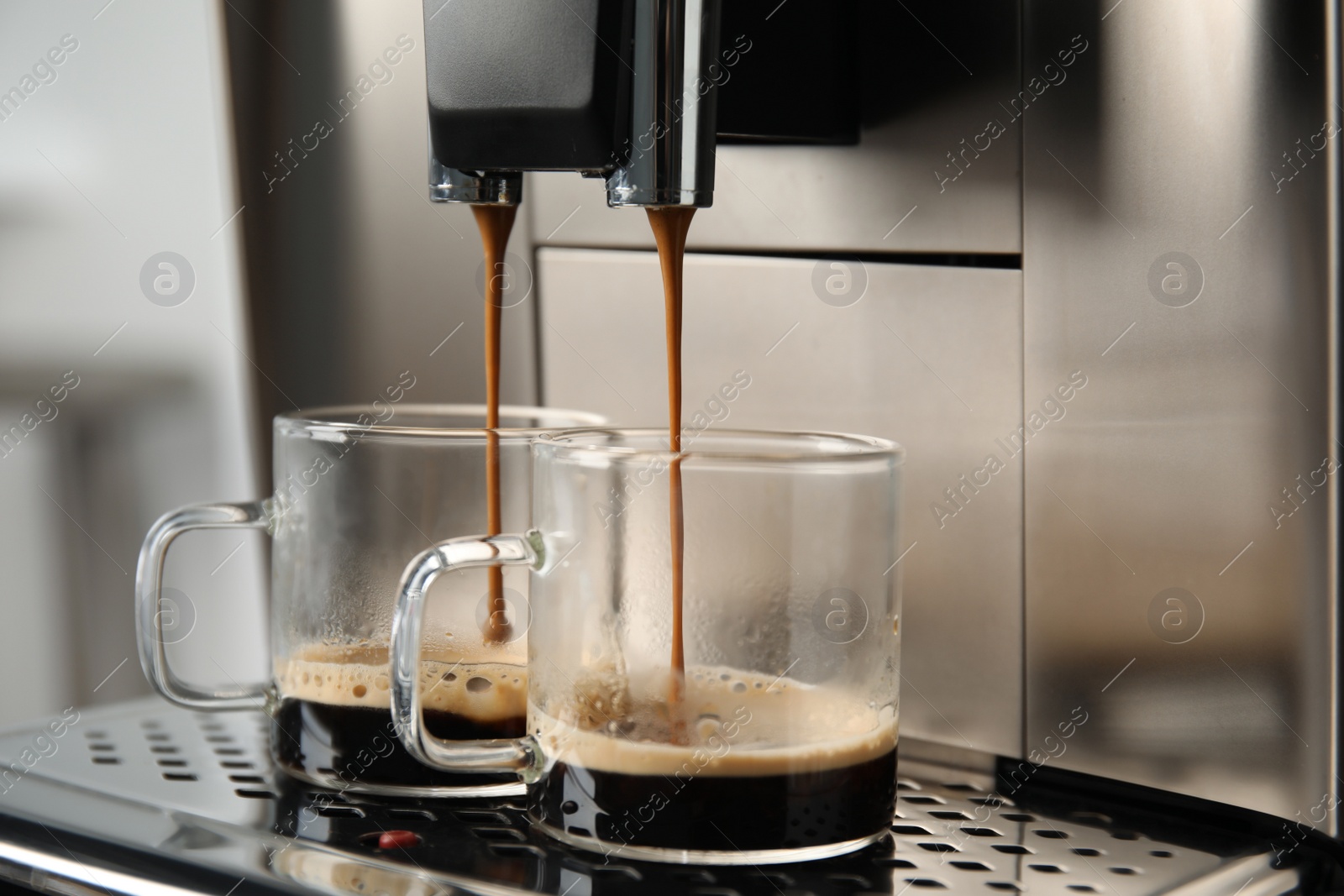 Photo of Espresso machine pouring coffee into glass cups against blurred background, closeup