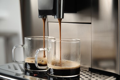 Photo of Espresso machine pouring coffee into glass cups against blurred background, closeup