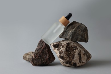 Photo of Glass bottle and stones on grey background