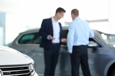 Photo of Blurred view of car dealership with salesman and client