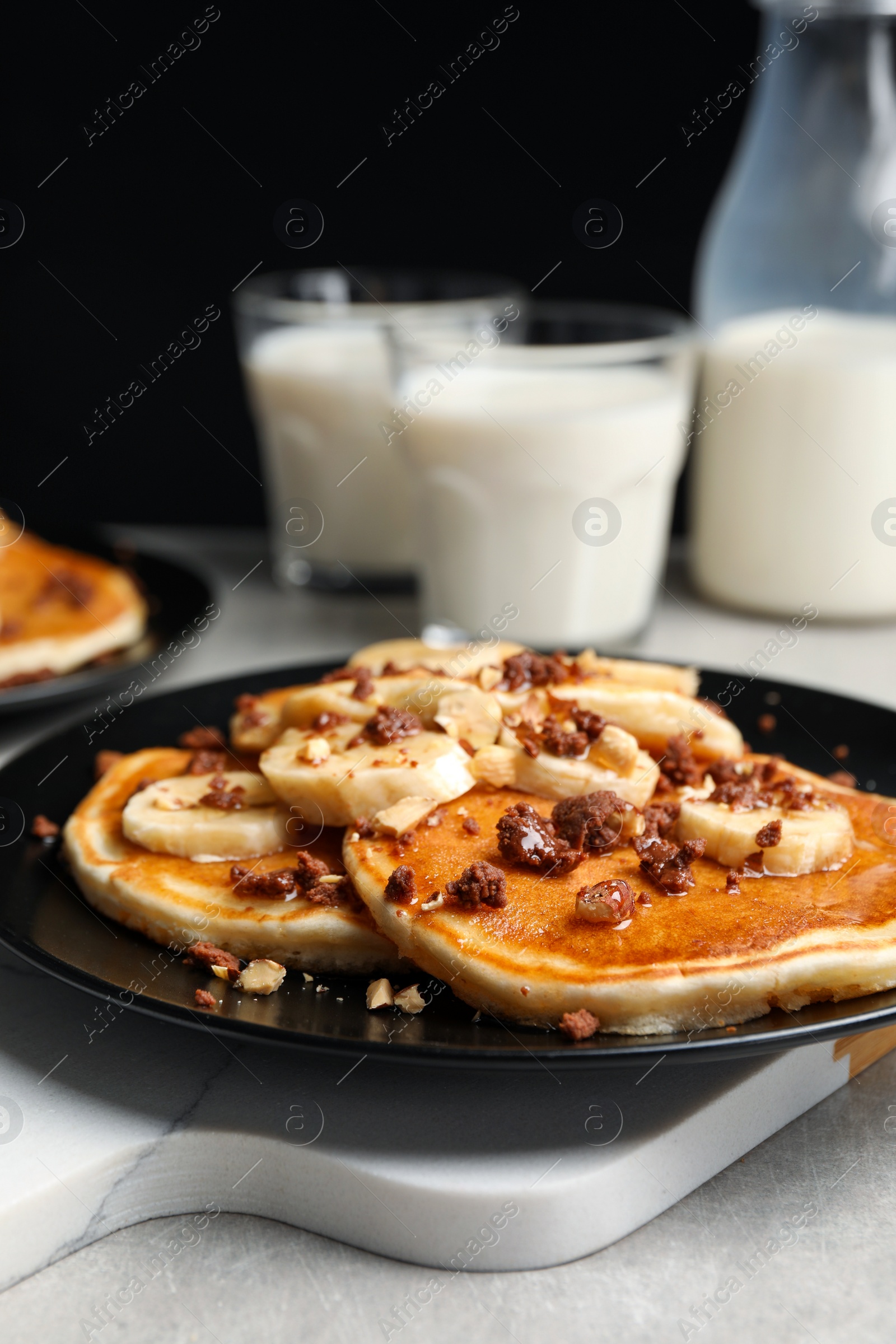 Photo of Tasty pancakes with sliced banana served on light grey table, closeup