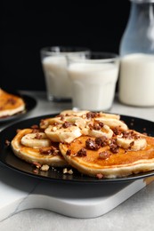 Tasty pancakes with sliced banana served on light grey table, closeup