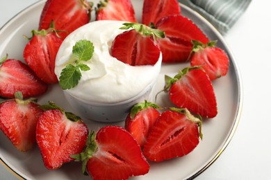 Delicious strawberries with whipped cream on white table, closeup