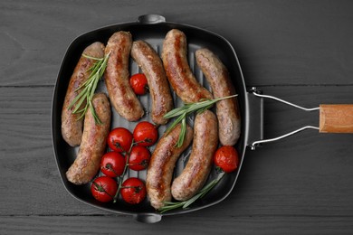 Photo of Grill pan with tasty homemade sausages, rosemary and tomatoes on grey wooden table, top view