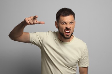 Photo of Aggressive man pointing on grey background. Hate concept